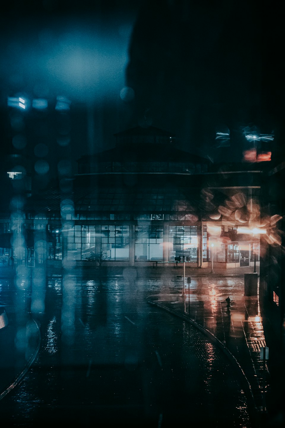 Człowiek idzie nocą po deszczowej ulicy miasta.
